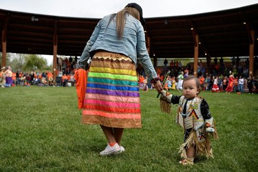 Shaunna Pierro looks down as she holds the hand of Akio Pierro at a memorial event marking the first anniversary of the discovery of unmarked Indigenous child graves at the Tk'emlups Pow Wow Arbour in Kamloops, B.C., May 23, 2022.