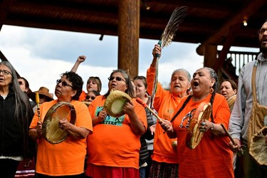 Evelyn Camille raises a feather as Tk'emlups te Secwepemc community members drum at a memorial event marking the first anniversary of the discovery of unmarked Indigenous child graves at the Tk'emlups Pow Wow Arbour in Kamloops, B.C., May 23, 2022.