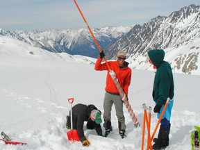 Ben Pelto, a glaciologist and UBC researcher, is holding a snow corer on the Kokanee Glacier, used to take snow cores to measure the density of the snow, Also pictured are Tom Hammond and Micah May.