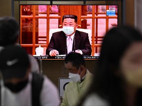 People sit near a screen showing a news broadcast at a train station in Seoul on May 12, 2022, of North Koreas leader Kim Jong Un appearing in a face mask on television for the first time to order nationwide lockdowns after the North confirmed its first-ever COVID-19 cases.