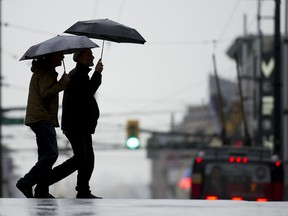 File photo of people walking with umbrellas on a day with rain and wind.