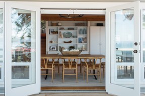 In the two-storey dining room, the design team kept the style simple and airy, with a streamlined live-edge dining table from Layers & Layers, iron chandelier from Circa Lighting and modern-classic wishbone dining chairs, sourced from Design Within Reach.