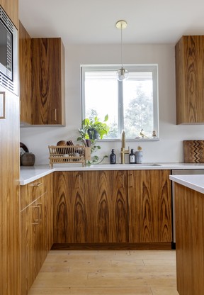 Bradley diseñó gabinetes de teca personalizados para complementar el amor de Weldon por el diseño de mediados de siglo, para una cocina decididamente moderna y funcional.