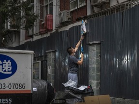 A man uses a pole to lift a package over a barrier wall with a resident under lockdown at an apartment building, after a recent COVID-19 outbreak on June 11, 2022 in Beijing, China.