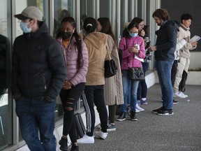 People wait to enter a Service Canada office on West Broadway in Vancouver on April 22. Two months later the long lineups haven't eased despite a hiring surge and other efforts to speed up the process.