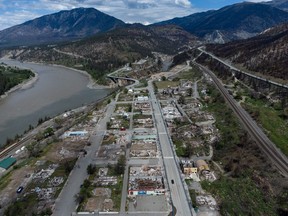 Vehicles travel on Main Street as the burned-out remains of businesses and properties destroyed by last year's devastating wildfire are seen in Lytton, B.C., Saturday, May 21, 2022. Rebuilding in the fire-ravaged village of Lytton, B.C., is likely to begin in September, according to the province's minister of public safety.
