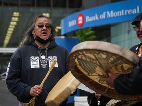 Maxwell Johnson, a Heiltsuk First Nation member who was arrested alongside his granddaughter as they were trying to open an account at the Bank of Montreal, sings and drums outside the bank's main branch before a news conference in Vancouver, on May 5, 2022.