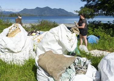 Marcie Callwaert, an educator at the Cedar Coast Field Station on Vargas Island near Tofino, B.C., with bags of plastic collected from the shore. The station offers researchers, students and others the opportunity to live off-grid.