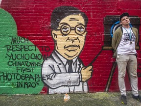 Downtown Eastside street artist Trey Helten by the mural he painted in Chinatown memorializing Chinese photographer Yucho Chow.