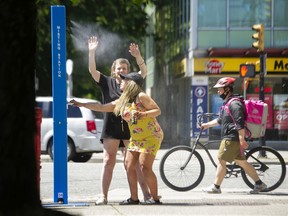 People cool off at a misting station on Commercial Drive in Vancouver.