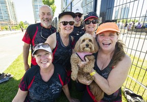 Das Maskottchen Sophie, das goldene Mini-Doodle, ist von den Mitgliedern des Drachenboot-Teams Brent Murphy, Nicole Asselin, Marlene Fox, Marianne Cook, Sally Simmons und Trish Wintle umgeben, während die Leute am Sonntag an den Drachenbootrennen in False Creek in Vancouver teilnehmen und sie sich ansehen.