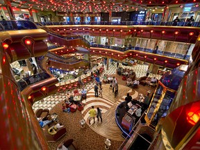 Guests aboard the Carnival Freedom enjoy cocktails and dancing in the Millennium Atrium.
