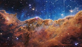 In this handout photo provided by NASA, a landscape of mountains and valleys speckled with glittering stars is actually the edge of a nearby, young, star-forming region called NGC 3324 in the Carina Nebula, on July 12, 2022 in space. Captured in infrared light by NASA's new James Webb Space Telescope, this image reveals for the first time previously invisible areas of star birth.