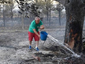 A man sprays water on the ground following a fire next to the village of Pumarejo, near Zamora, northern Spain, on July 18, 2022.