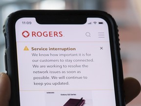 A person looks at their cellphone displaying a Rogers service interruption alert in Montreal, Friday, July 8, 2022.