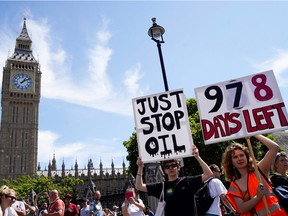 Demonstrators hold placards reading messages against the use of fossil fuels as they take part in a protest march arriving at Parliament Square, in London, on July 23, 2022. Photo: Niklas HALLE'N / AFP