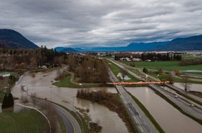 A Tiger Dam is placed across all lanes of the closed Trans-Canada Highway near the flooded Sumas River, in Abbotsford, BC, on Wednesday, December 1, 2021. Solutions could include upgrading the levees and raising their height, but also moving or removing them .  and home purchases to restore floodplains in BC's most populous region.