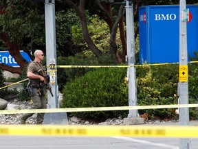 A police officer looks on after two armed men entering a bank were killed in a shootout with the police in Saanich on June 28, 2022.