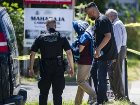 Various police agencies investigate the shooting death of Ripudaman Singh Malik at 8236 128th Street in Surrey, B.C. Thursday morning July 14, 2022. Malik, a well-known Surrey businessman, was acquitted in 2005 in the Air India Bombing, which killed hundreds of people in 1985. Pictured is an unknown woman, identity shielded, at the crime scene.