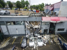 Emergency services personnel investigate a collapsed parking garage roof at a business on E. Broadway near Rupert Street in Vancouver on Friday, July 15, 2022. The roof collapsed Thursday afternoon, sending several people to the hospital.