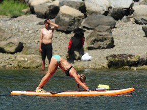 A woman practices yoga on a paddle board in False Creek in Vancouver.