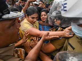 Former member of parliament Hirunika Premachandra (middle) tries to jump over the barriers while pushed by supporters, during a protest outside Sri Lanka's Prime Minister Ranil Wickremesinghe's private residence in Colombo on June 22, 2022.