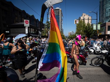A rainbow flag is flown from a hockey stick as people gather while waiting for Dykes on Bikes to lead the start of the Vancouver Pride Parade, in Vancouver, on Sunday, July 31, 2022.
