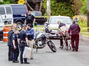 The body of a suspect is removed from the scene of a robbery at the Bank of Montreal at Shelbourne and Pear streets on Tuesday. Two suspects, identified as twin brothers Issac and Mathew Auchterlonie of Duncan, were killed in a shootout with police.