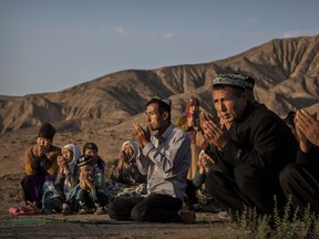 A Uyghur family pray at the grave of a loved one on the morning of the Corban Festival on September 12, 2016 at a local shrine and cemetery in Turpan County, in the far western Xinjiang province, China.