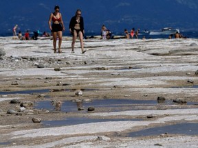 People walk as underwater rocks emerge from the water of Lake Garda after northern Italy experienced the worst drought in 70 years in Sirmione, Italy, Aug. 16, 2022.