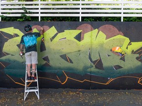 Graffiti artist Theme works on a creation at the Holden Courage Graffiti Jam as part of the Vancouver Mural Festival in Vancouver on Saturday.