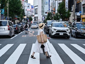 A pedestrian crosses the street in the Shinjuku district of Tokyo on August 16, 2022. (Photo by Richard A. Brooks / AFP)