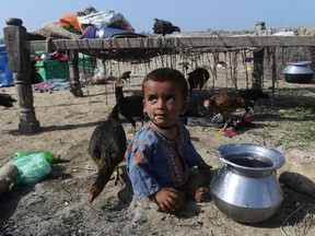 A child sits on a dry ground near by his family after fleeing from flood hit home in Shikarpur of Sindh province on August 30, 2022.  (Photo by Asif HASSAN / AFP)
