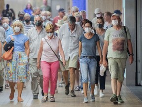 People wear face masks as they walk through a subway station in Montreal, Sunday, July 17, 2022, as the COVID-19 pandemic continues in the province.