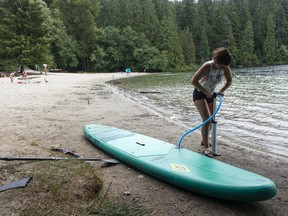 A woman inflates her stand-up paddleboard at White Pine Beach on Sasamat Lake in Port Moody in August 2022.