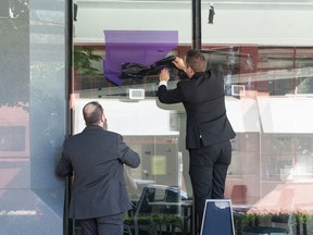 NPA signs are taken down at the civic party’s Wall Centre office in Vancouver on Friday, Aug. 5, 2022. One of the men removing the signs identified himself as working for the building’s strata. NPA mayoral candidate John Coupar announced he was resigning from the mayoral race early Friday.
