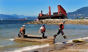 Workers are seen in front of the derelict barge at English Bay in Vancouver as dismantling begins in early August. The work should take between 12 and 15 weeks to complete.