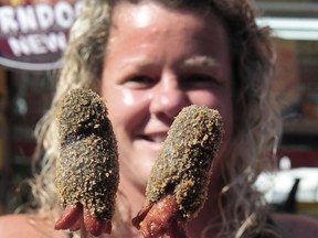 Karlye Dennis of Little Coco's Corn Dogs  in action with the Korean Squid Ink Corn Dog during a media event to promote the new dishes available this year at the PNE in Vancouver,  BC., on August 24, 2022.