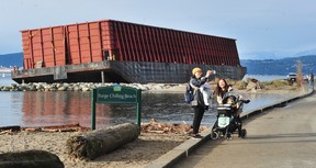 Eine Frau posiert für ein Selfie, nachdem das Vancouver Parks Board am 15. Dezember 2021 ein Barge Chilling Beach-Schild in der Nähe des Lastkahns in der English Bay aufgestellt hat.