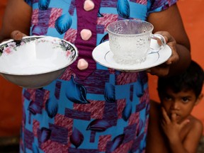 Chandra Thushari Peiris, 42, poses with a cup and dish which she uses at her food kiosk while her grandson looks on, amid the country's economic crisis, in Colombo, Sri Lanka, August 7, 2022.