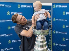 Darcy Kuemper holds nine-month-old Ben Koenning in the Stanley Cup at the Saskatoon Police Service gymnasium Friday.