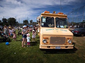 People buy ice cream from one of Meedo Falou's Rainbow Ice Cream trucks in Tsawwassen on Monday, Aug. 1, 2022. Much of Canada has been sweltering, but that's cold comfort for ice cream truck vendors like Falou, who says inflation and high fuel costs are melting away his profits.
