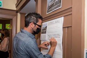 A visitor signs the comment board at the opening night of a photography exhibit featuring work that West End seniors shot during the pandemic lockdown. The event took place at Vancouver’s Barclay Manor, on Sept. 28, 2022.