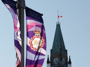 A banner celebrating Queen Elizabeth’s Platinum Jubilee is seen as the Canadian flag flies at half-mast on top of the Peace Tower at the Parliament Buildings in Ottawa on Sept. 8, 2022.