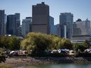 Tents are seen at a homeless camp in Club Park with the downtown Vancouver skyline in the background on Sunday, August 14, 2022. Families with incomes who can't afford rent and people in tents who fear they'll die homeless, according to Canada's federal housing advocate.