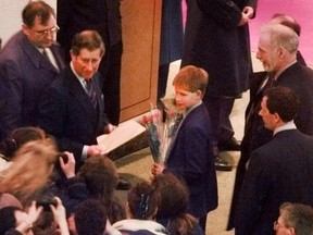Prince Charles and his son Prince Harry accept some flowers from admirers as they arrive at the Waterfront Hotel in Vancouver. (Jon Murray/PNG)