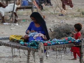A woman, who became displaced, looks after her baby while taking refuge in a camp, following rains and floods during the monsoon season in Sehwan, Pakistan September 15, 2022. REUTERS/Akhtar Soomro