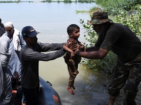 Pakistan’s navy members discharge flood victims from a boat after they were rescued from a flooded village, following rains and floods during the monsoon season in Khairpur Nathan Shah, Pakistan September 3, 2022. REUTERS/Yasir Rajput.