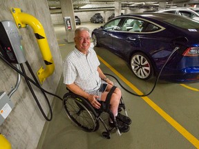 Jacques Courteau beside his Tesla with charging station in the underground parking lot of his home in Vancouver.