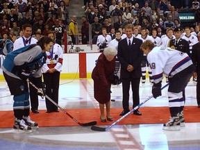 Her Royal Highness Queen Elizabeth II drops the puck during a ceremonial face-off between Vancouver Canucks captain Markus Naslund and San Jose Sharks player Mike Ricci on Oct. 6, 2002.
